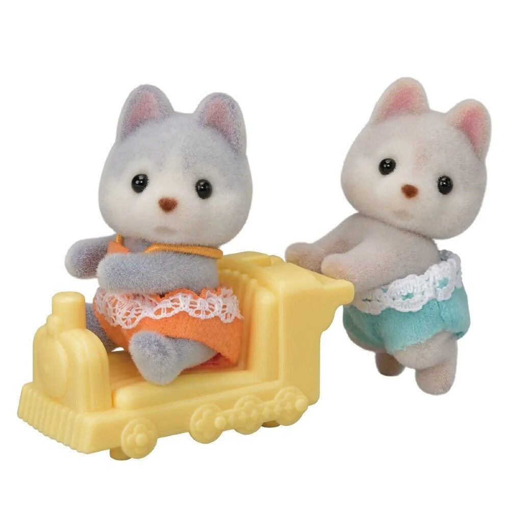2 baby dog figures from the Sylvanian Families Husky Twins set, depicting one husky sitting in a little yellow train with the second husky behind it