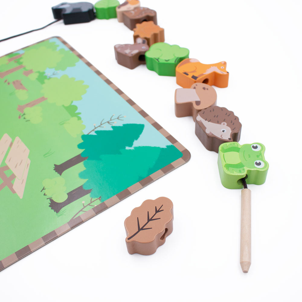 The Woodland themed lacing game from Jumini, with wooden figures including badger, hedgehog, fox, squirrel, bird, mushroom and leaves, all sitting next to a scenery board and laced together with a thread
