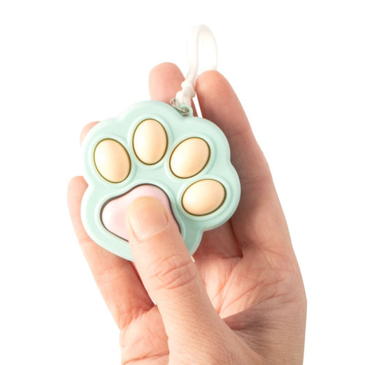 A cat paw shaped sensory fidget clicker toy from Keycraft held in a hand on a white background