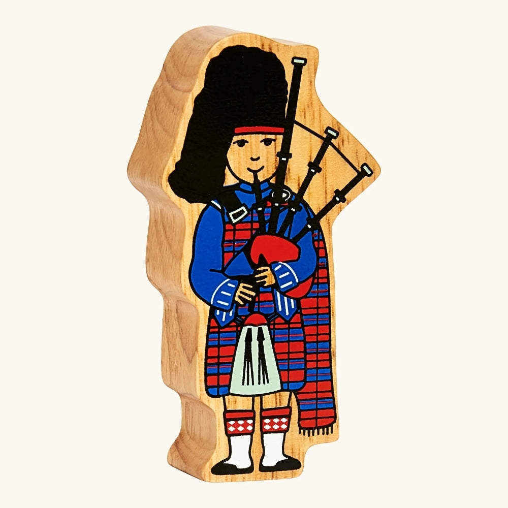 A solid wooden figure of a Scottish Bagpiper in full tartan red and blue kilt from Lanka Kade