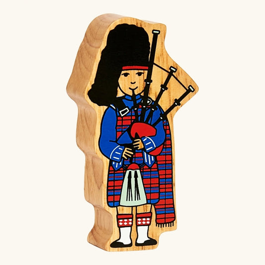 A solid wooden figure of a Scottish Bagpiper in full tartan red and blue kilt from Lanka Kade