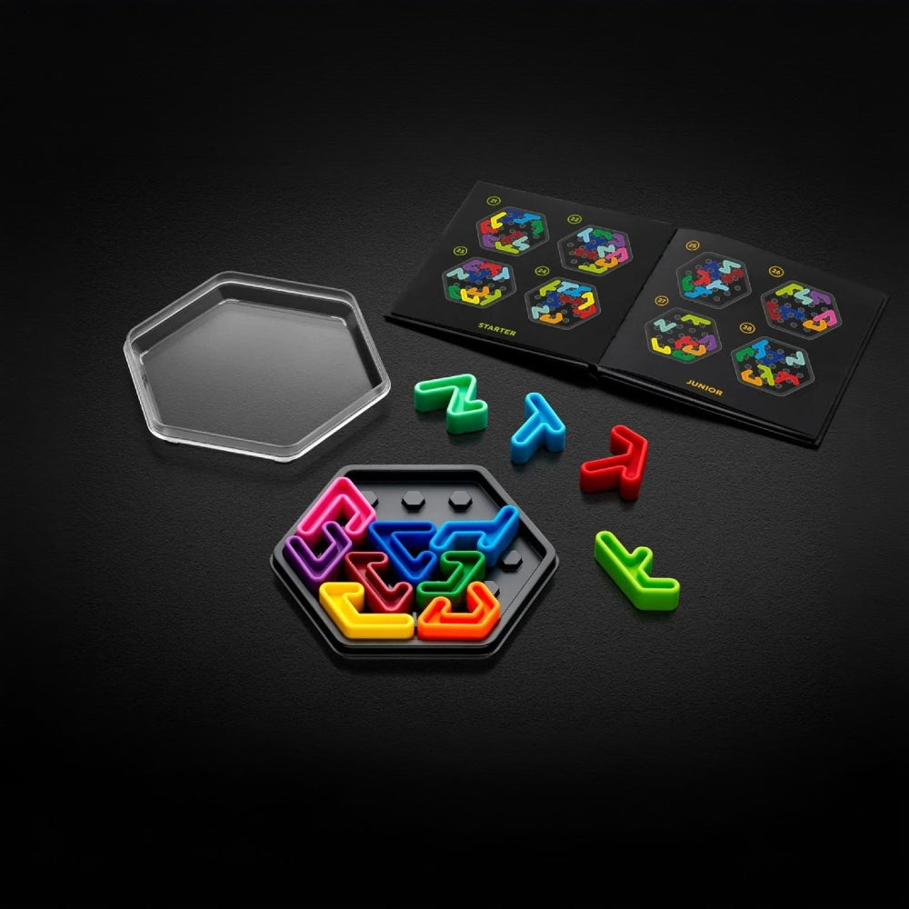 A colourful logic puzzle game set displayed on a dark background, including a clear hexagonal lid, a black hexagon tray filled with brightly coloured pieces, loose coloured pieces, and the challenge book
